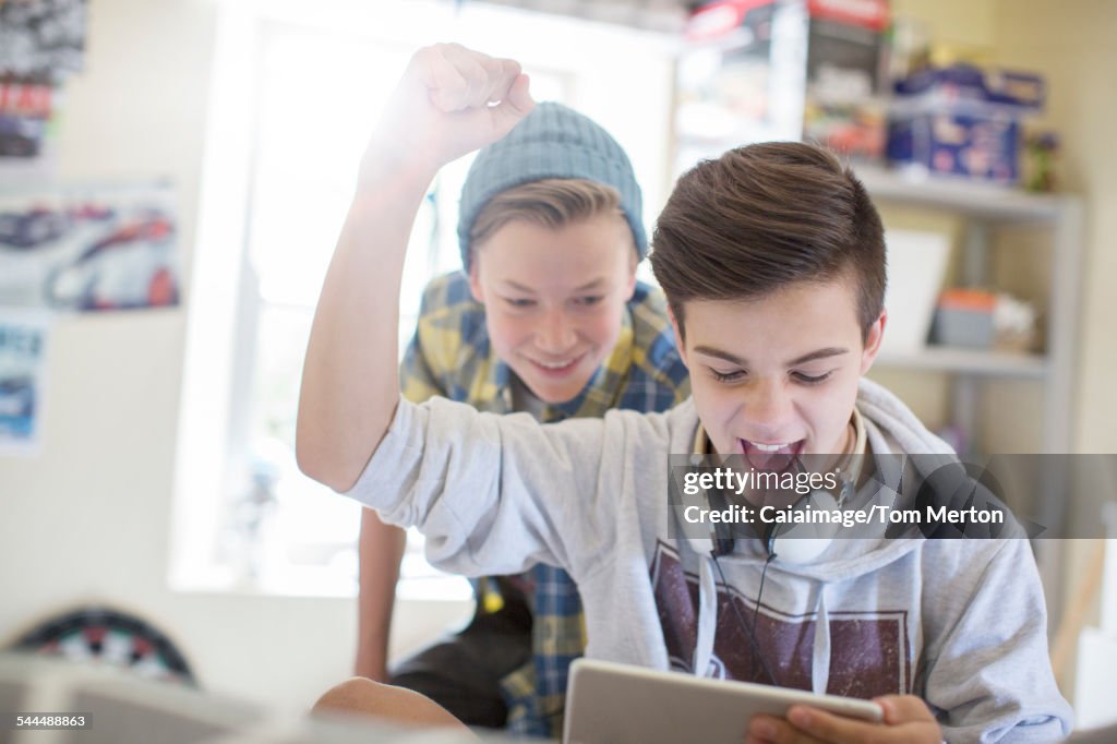 Two teenage boys having fun while using digital tablet