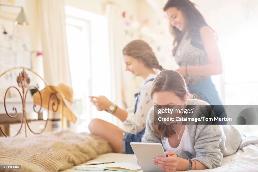 Three teenage girls relaxing in bedroom