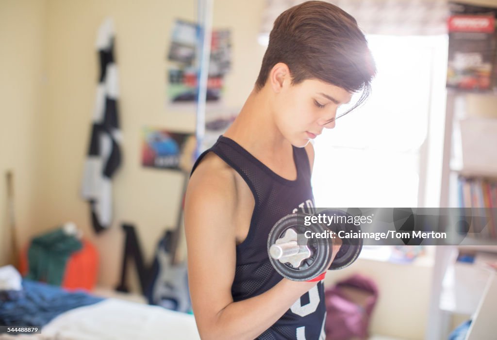 Teenage boy exercising with dumb bell