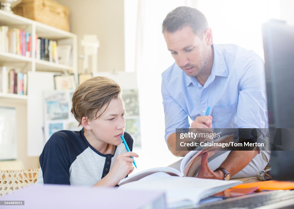 Father helping teenage son with his homework