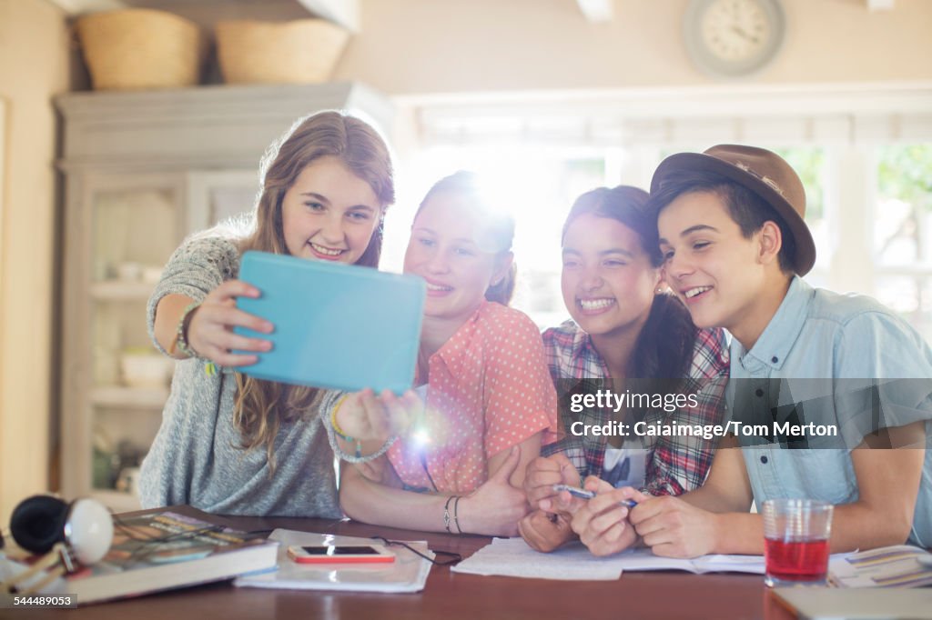 Group of smiling teenagers taking selfie in dining room