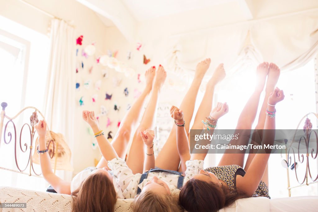 Tres adolescentes acostadas en la cama con los pies en alto