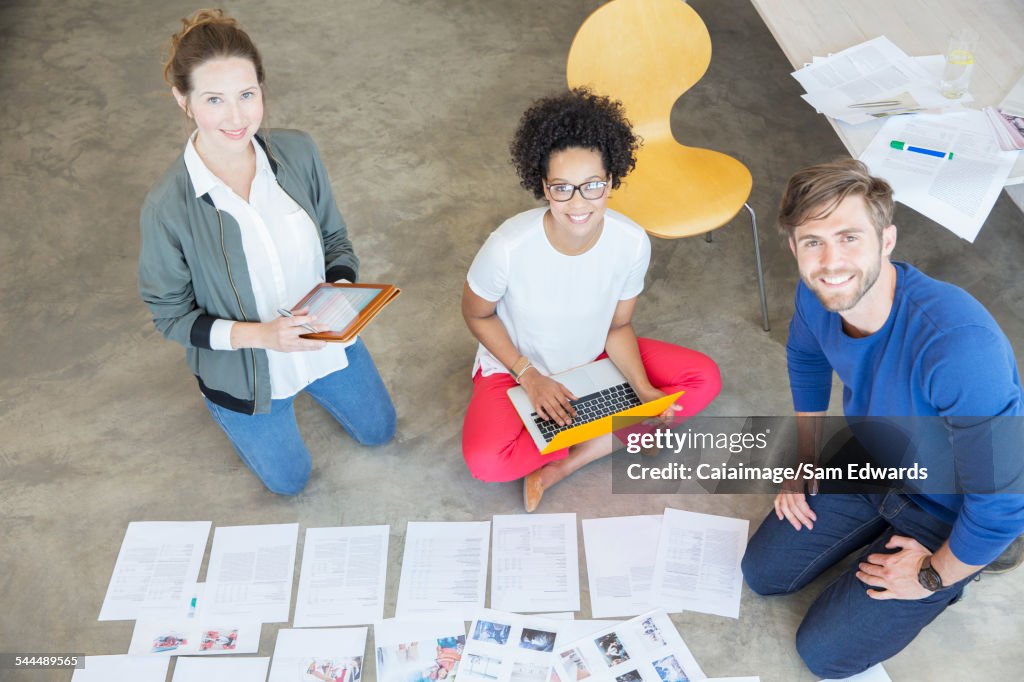 Portrait of three young people sitting on floor and working together in studio