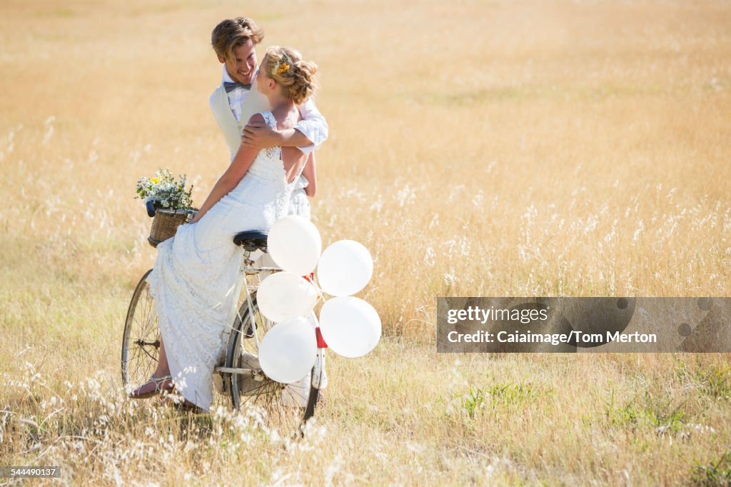 Bride and bridegroom riding bike with balloons attached