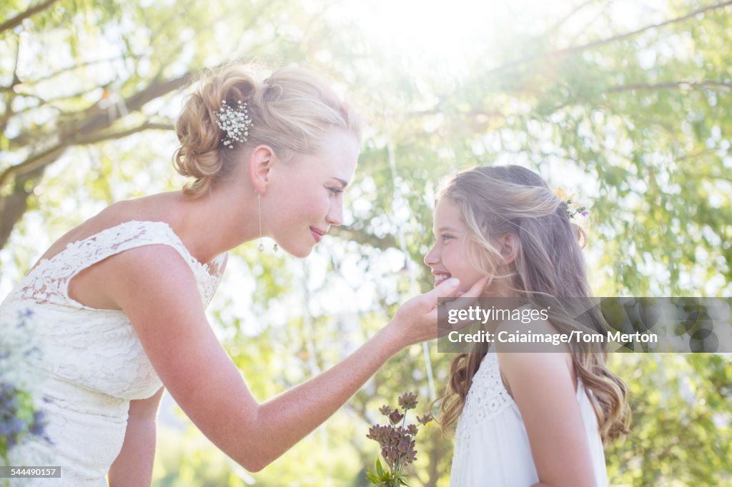 Bride and bridesmaid facing each other in domestic garden during wedding reception