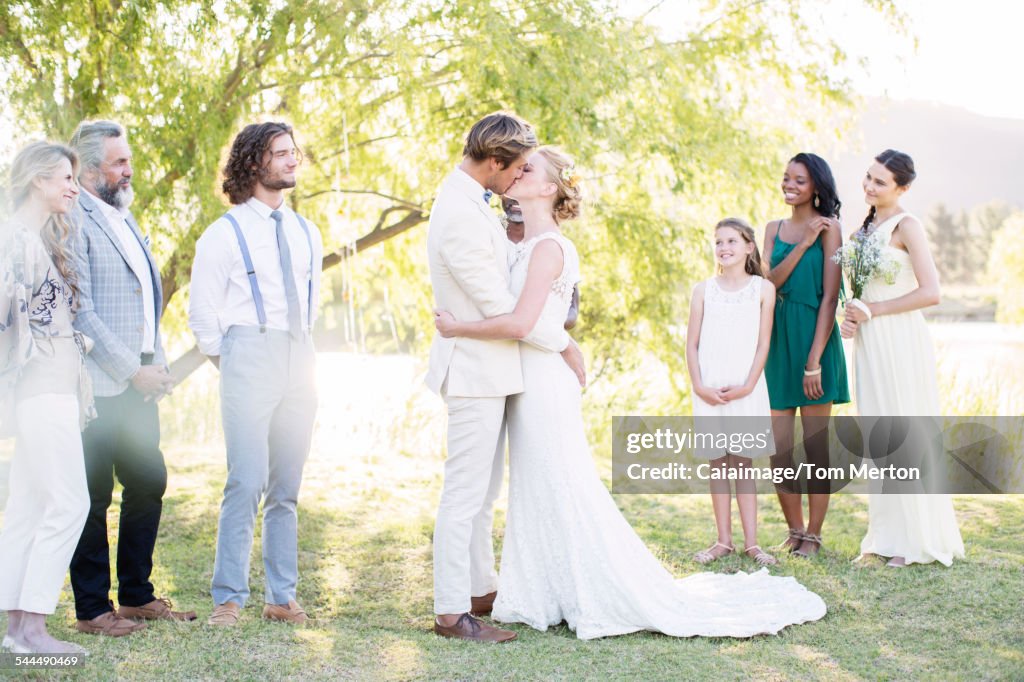 Young couple embracing and kissing during wedding ceremony in domestic garden