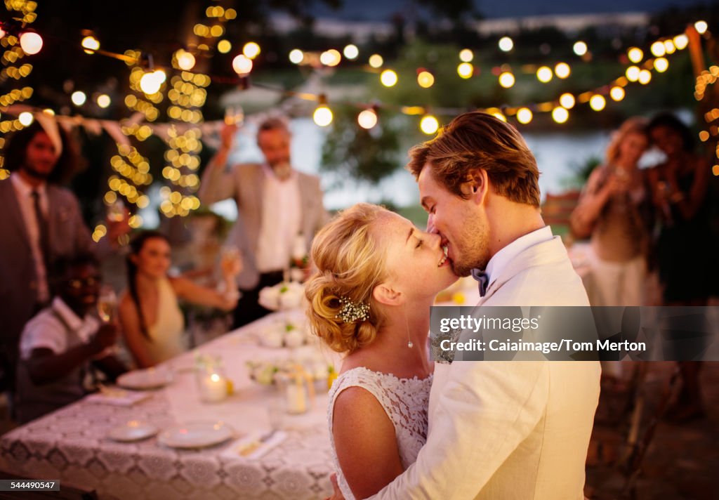 Young couple kissing during wedding reception in domestic garden