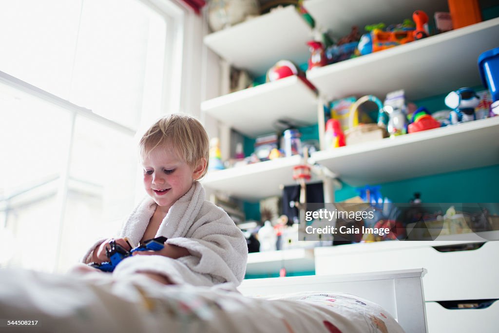 Boy sitting in bed in his room playing with toy