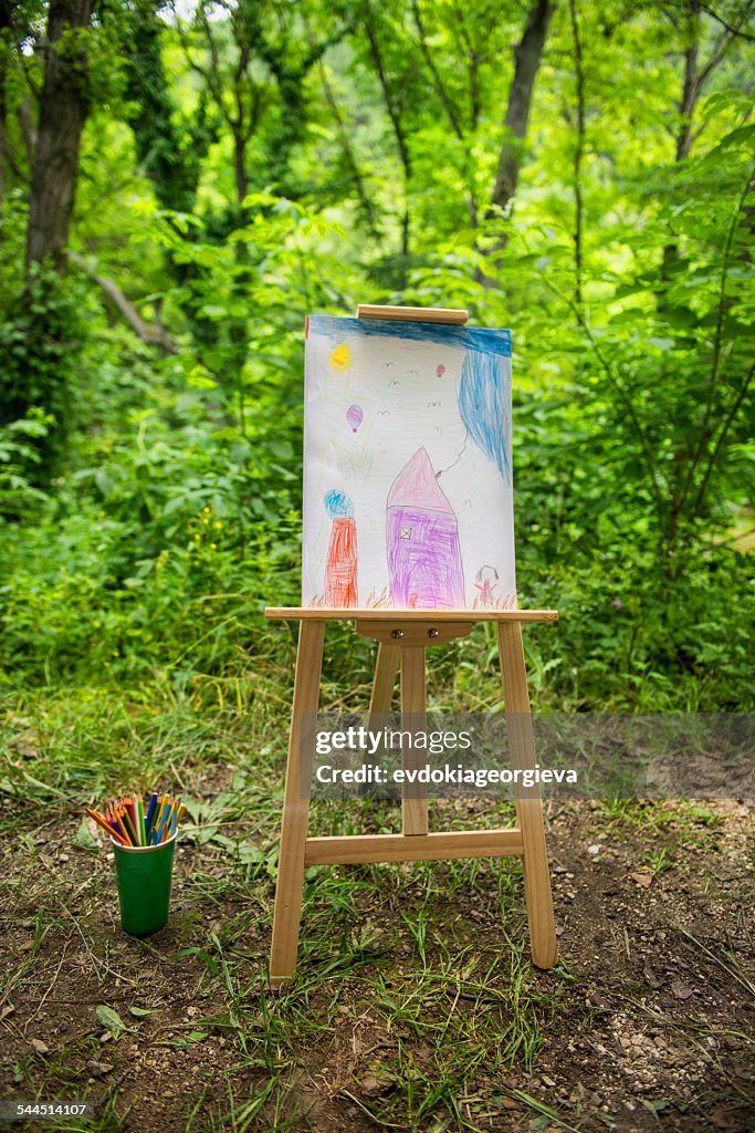 Easel with child's drawing in forest