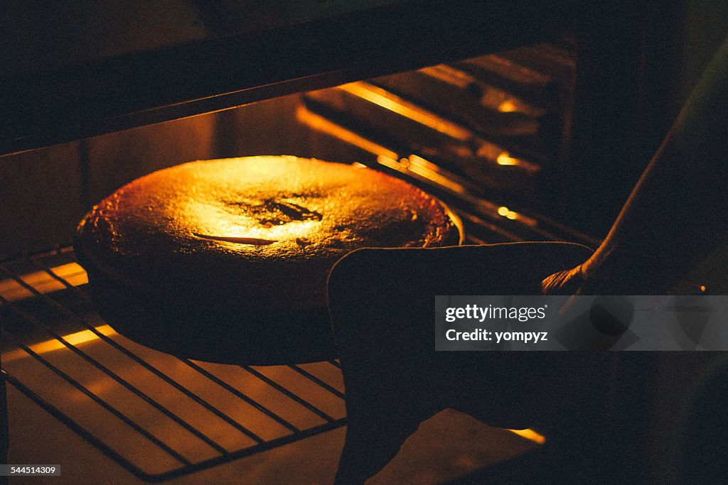 Woman baking cake in oven