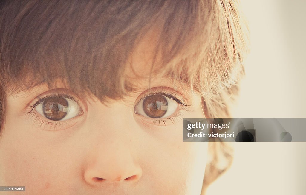 Boy (2-3) with big eyes staring at camera