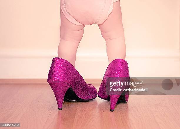 toddler wearing mother's shoes - baby shoes stock-fotos und bilder