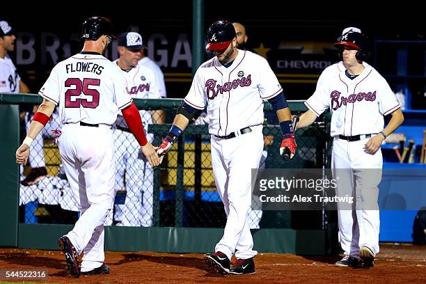 JUlLY 3: Tyler Flowers is greeted in the dugout after scoring a run in the ninth inning during the game against the Miami Marlins at Fort Bragg...