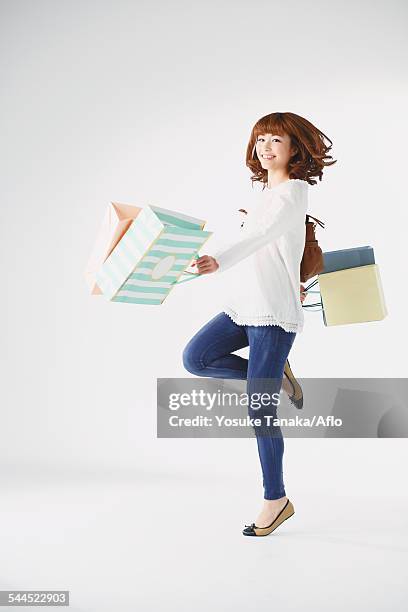 full length portrait of young japanese woman against white background - frau tüte einkaufen stock-fotos und bilder