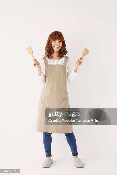 full length portrait of young japanese woman against white background - apron woman photos et images de collection