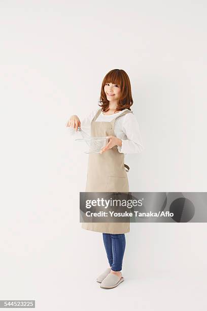 full length portrait of young japanese woman against white background - apron isolated stockfoto's en -beelden