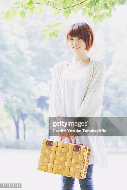 portrait of young japanese woman in a park - tuniek stockfoto's en -beelden