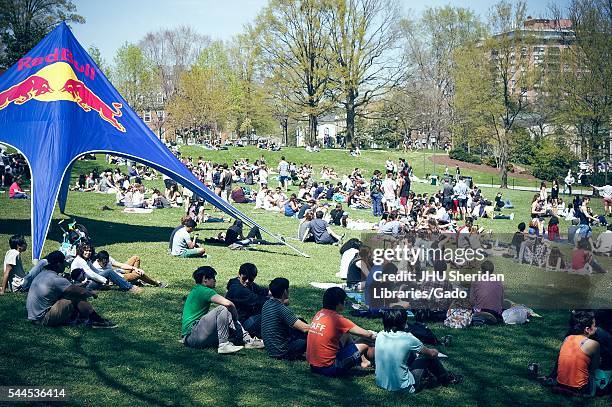 Dozens of students huddle and sunbathe on the grassy Beach, with drinks all around and a large Red Bull tent to the left, during Spring Fair, a...