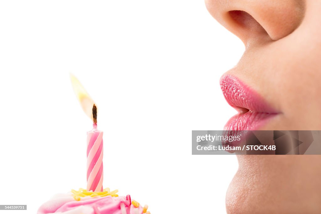 Young woman blowing out birthday candle, close-up