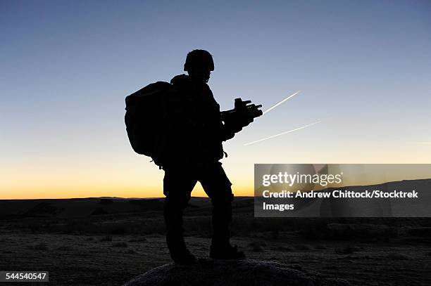 a british soldier on patrol as the sun rises at sennybridge training area, wales, united kingdom. - forze armate britanniche foto e immagini stock