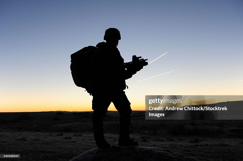 A British soldier on patrol as the Sun rises at Sennybridge Training Area, Wales, United Kingdom.