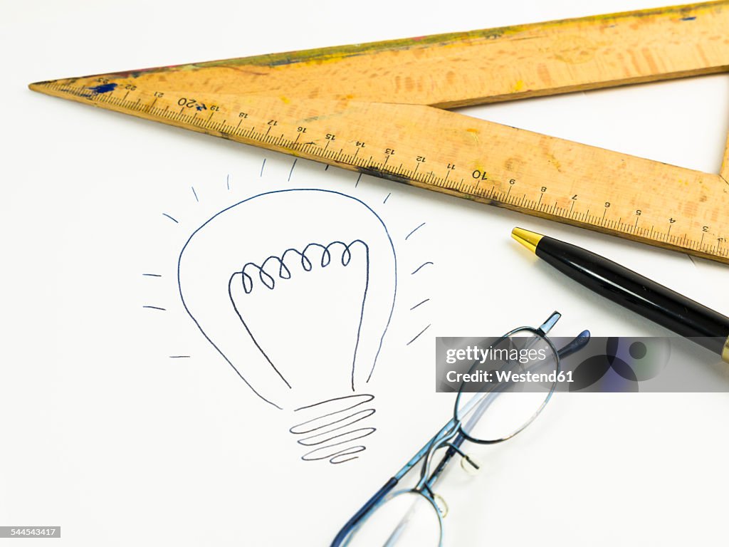 Drawn lightbulb, set square, reading glasses and ballpen on white paper