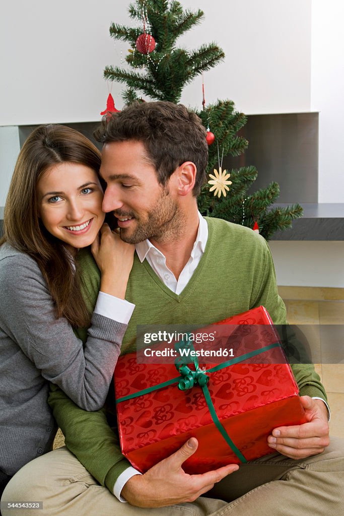 Happy couple with Christmas present at home