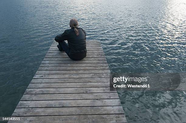 man sitting on wooden boardwalk at lake - one man only stock pictures, royalty-free photos & images