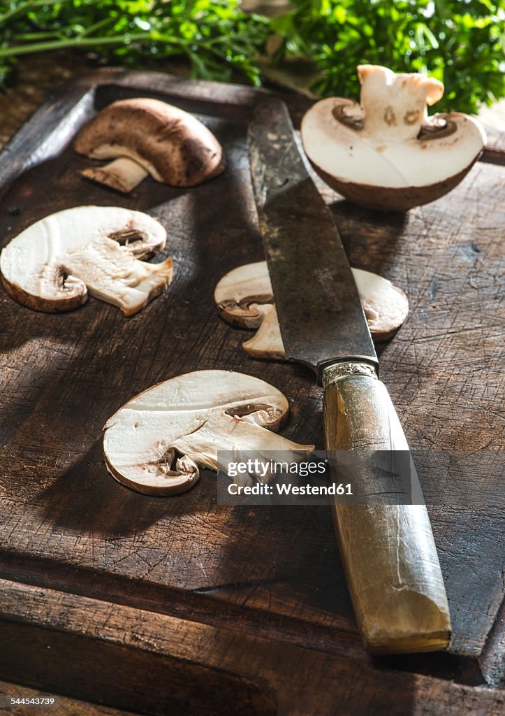 Sliced mushrooms and knife on wooden board