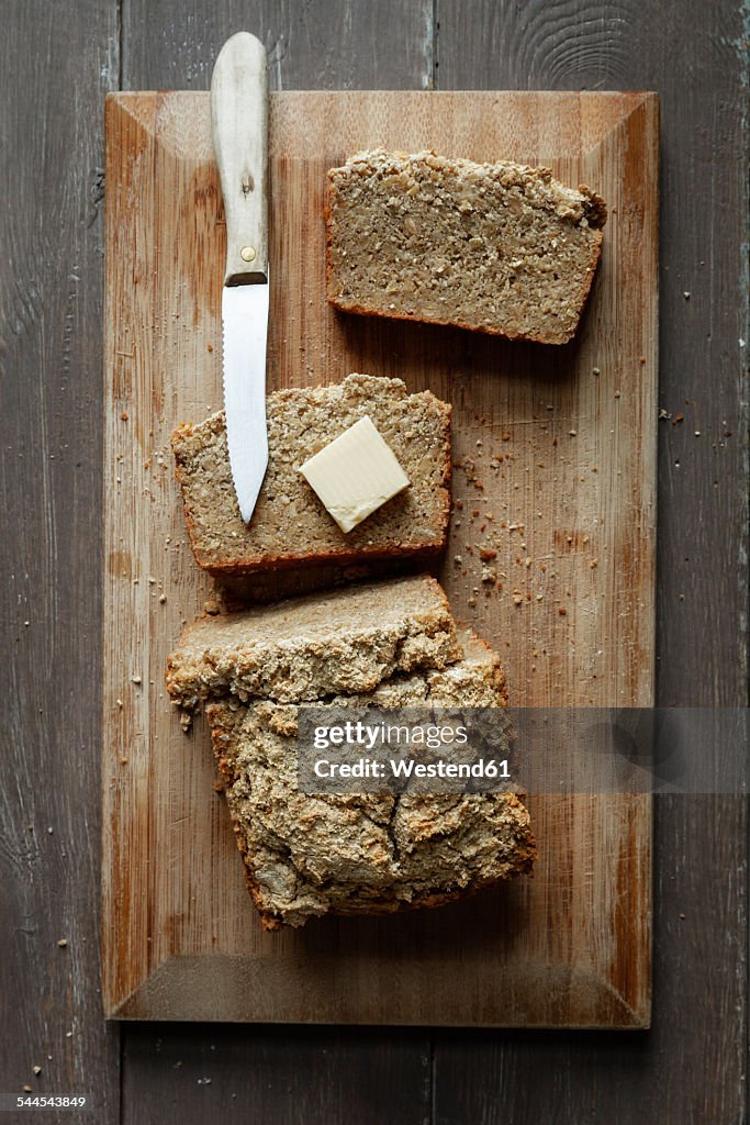 Home-baked glutenfree buckwheat bread, piece of butter and kitchen knife wooden board