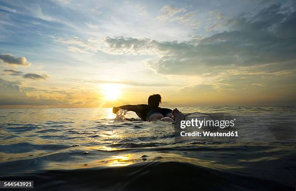indonesia, bali, canggu, young woman at her surfboard by twilight - allongé sur le devant photos et images de collection