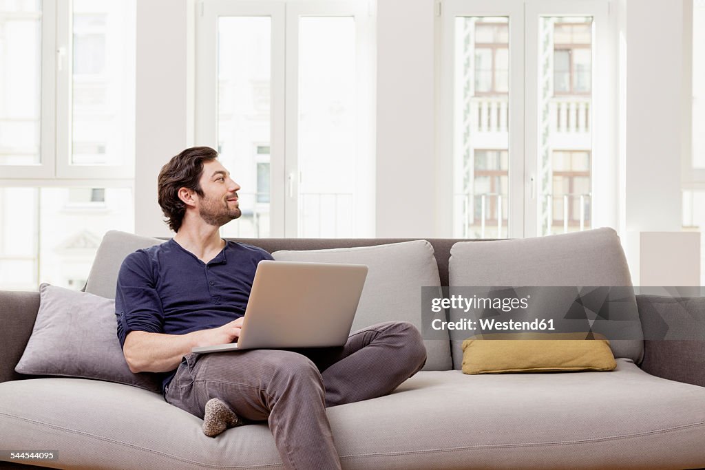 Man sitting on couch using laptop