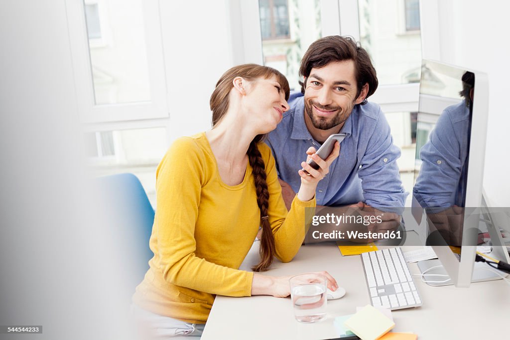 Couple with cell phone at desk in home office