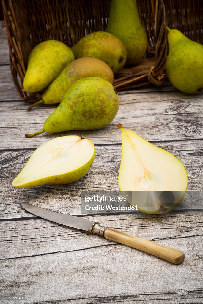 Wickerbasket, pears and pocket knife on grey wood