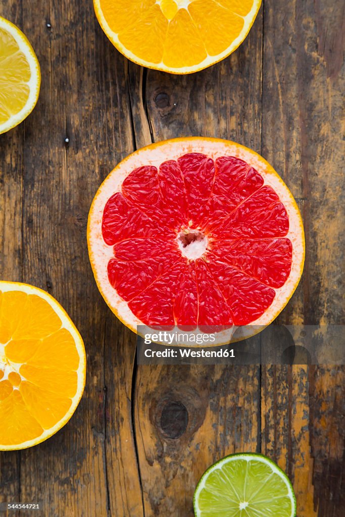 Slices of different citrus fruits on dark wood