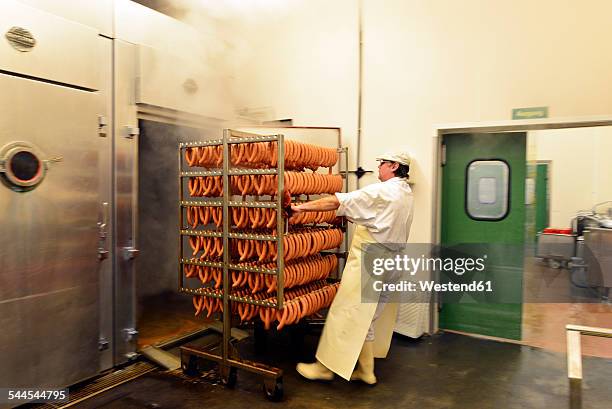 man pulling sausages out of smokehouse in a butchery - smoking meat stock pictures, royalty-free photos & images