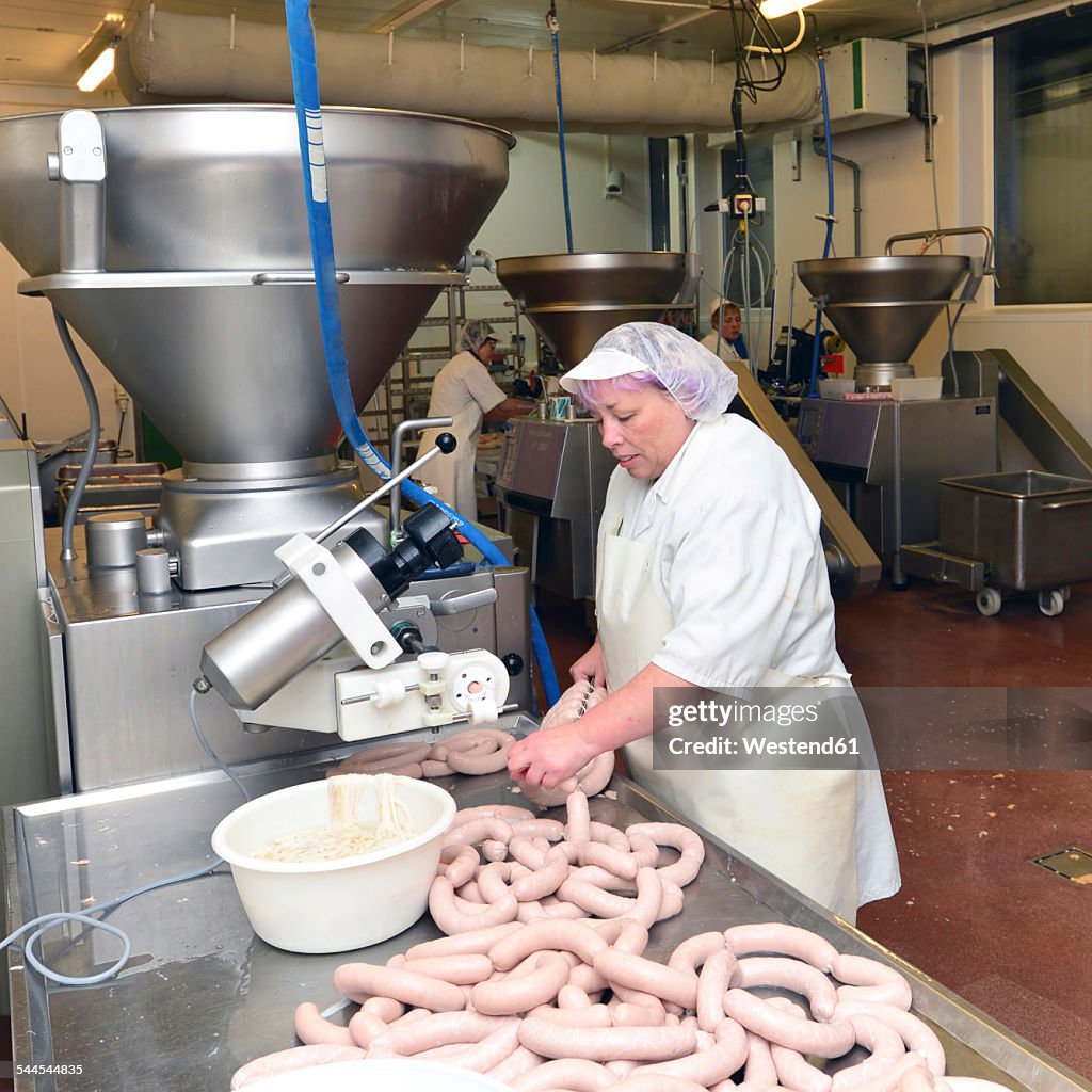 Woman working at sausage production in a butchery