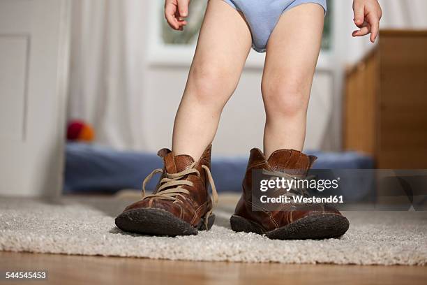 toddler in father's shoes - baby shoes stock-fotos und bilder