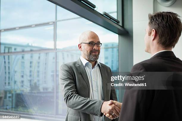 two businessmen shaking hands in office - handshake business zwei personen stock-fotos und bilder