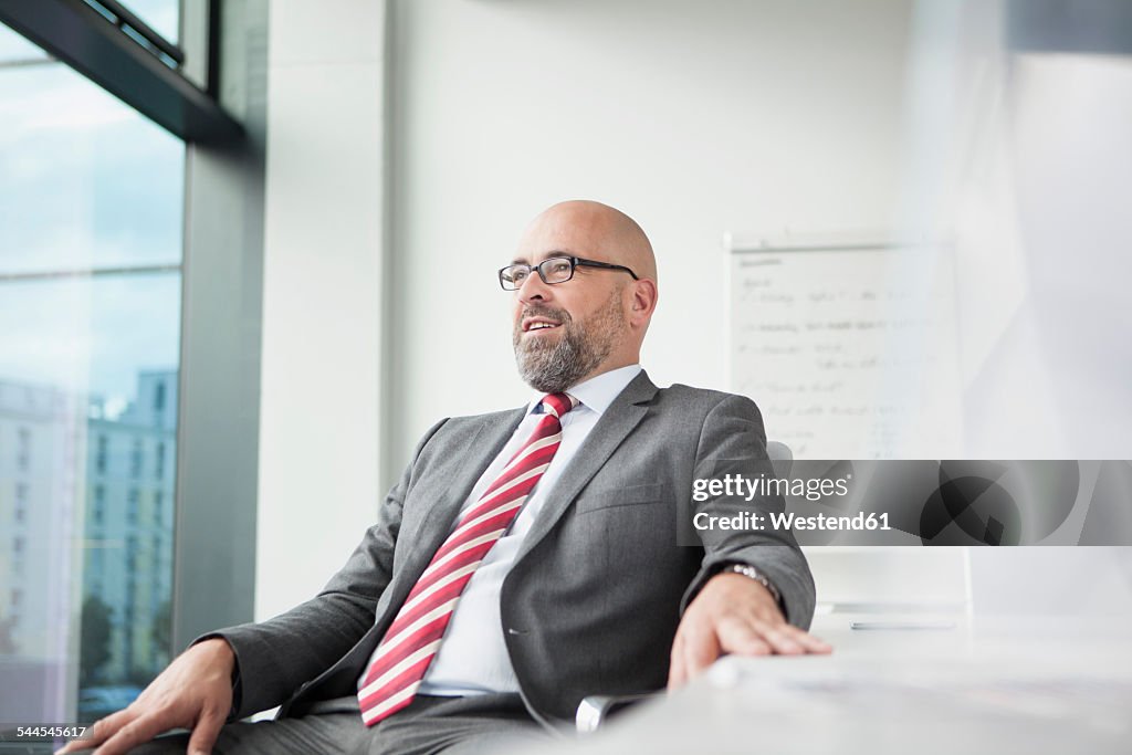 Confident businessman in office looking out of window
