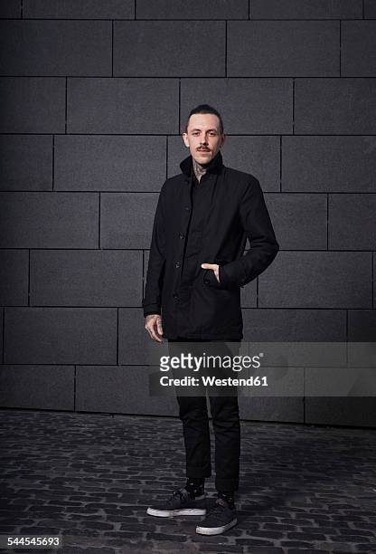 portrait of black dressed man in front of grey background - zwart jak stockfoto's en -beelden