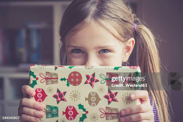 little girl holding christmas present - gift lounge foto e immagini stock