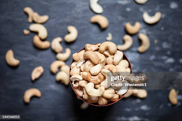 bowl of roasted and salted cashew nuts on slate - cashewnuss stock-fotos und bilder