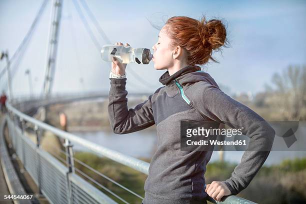 young woman drinking water out of a bottle after jogging - sport drinking bottle stock-fotos und bilder