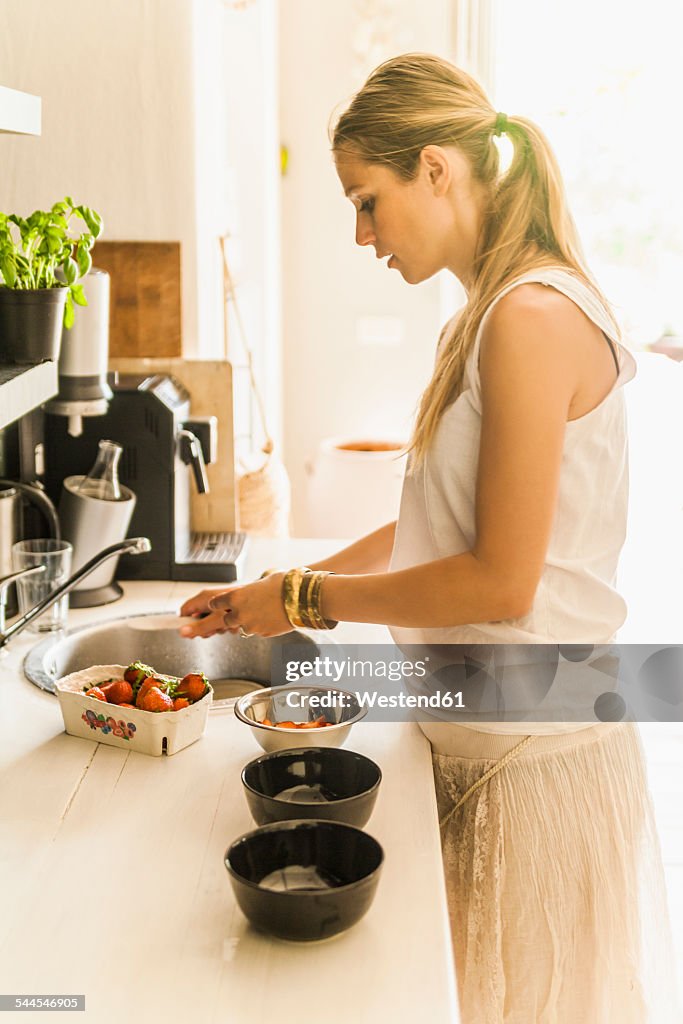 Woman preparing strawberries in kitchen