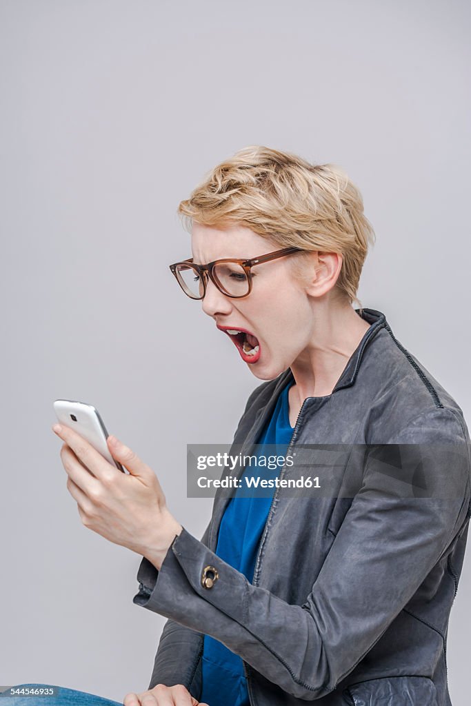 Blond woman looking at her smartphone screaming