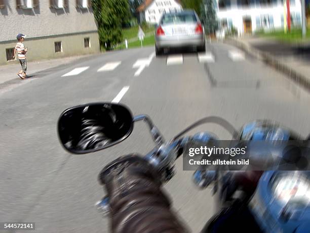 Motorradfahrer auf einer Landstrasse, Verkehrssituation aus Sicht des Fahrers, am Zebrastreifen will ein Kind die Strasse überqueren