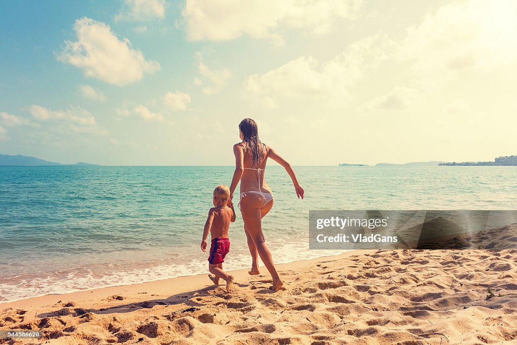 Madre con bebé runnig en playa tropical