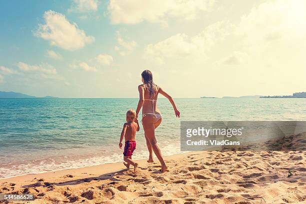 mother with baby runnig at tropical beach - beautiful beach babes 個照片及圖片檔