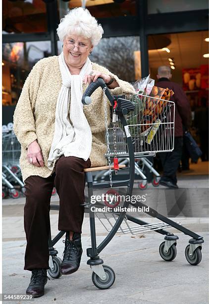 Deutschland, Berlin, "Generationen-Markt" der Supermarktkette Kaiser's, Aeltere Dame vor dem seniorengerechten Supermarkt mit einem Einkaufswagen mit...